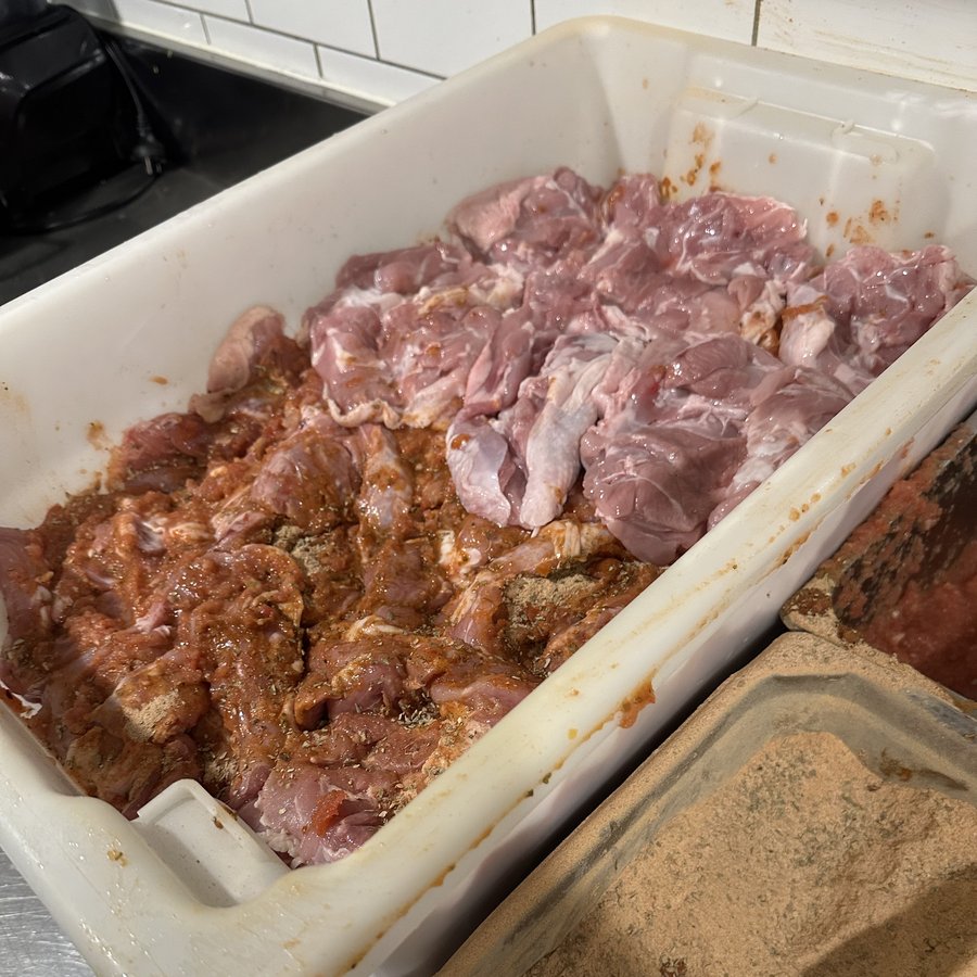 Large trays of chicken maryland and lamb shoulder packed with Yassas housemade herb marinade ready for 24-hour rest - Yassas Greek kitchen